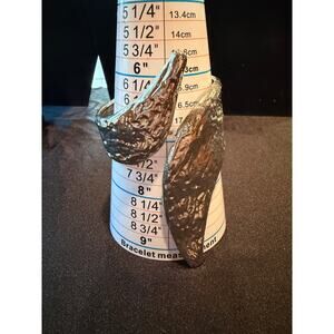 Bracelet is a textured silver tone cuff bracelet, "molten" leaf design